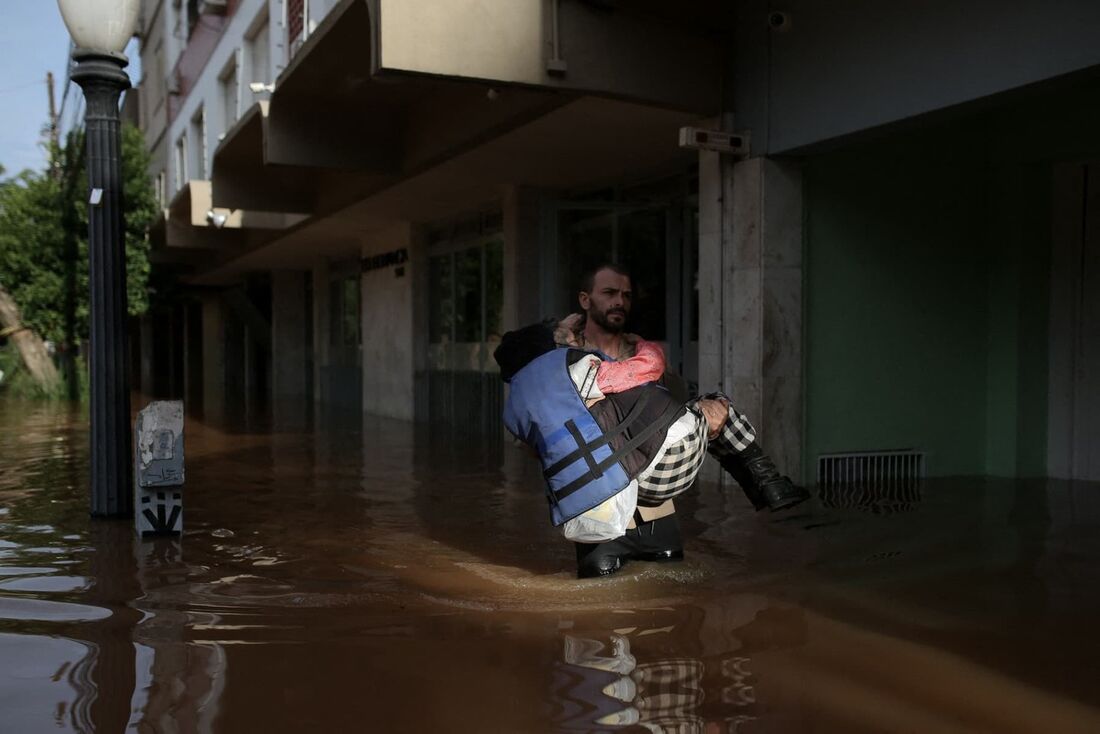 Um voluntário resgata Carmelina Castro, 79 anos, de uma área alagada no bairro Cidade Baixa, em Porto Alegre.