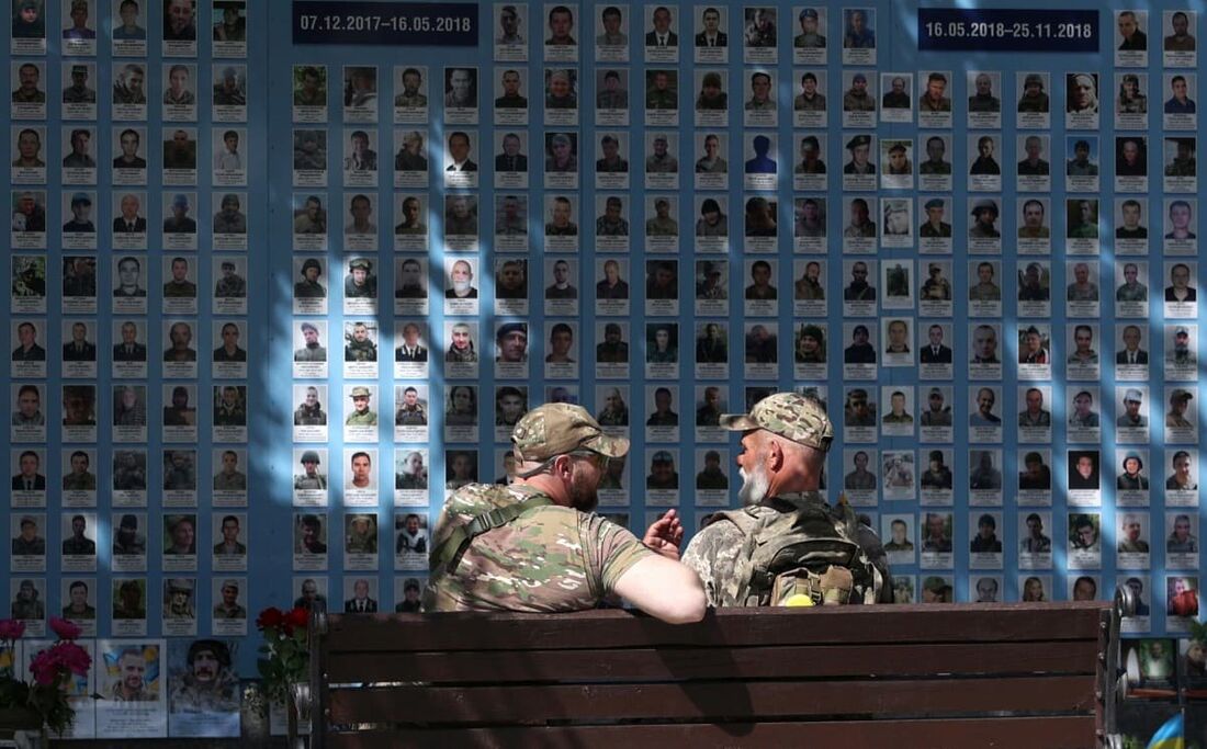 Dois militares ucranianos conversam em frente ao ''Muro em Memória dos Caídos pela Ucrânia", um memorial aos soldados ucranianos, no centro de Kiev