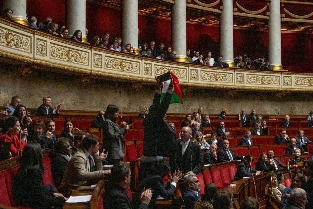 O esquerdista francês La France Insoumise (LFI), membro do parlamento, Sebastien Delogu agita uma bandeira nacional palestina durante uma sessão de perguntas ao governo na Assembleia Nacional em Paris