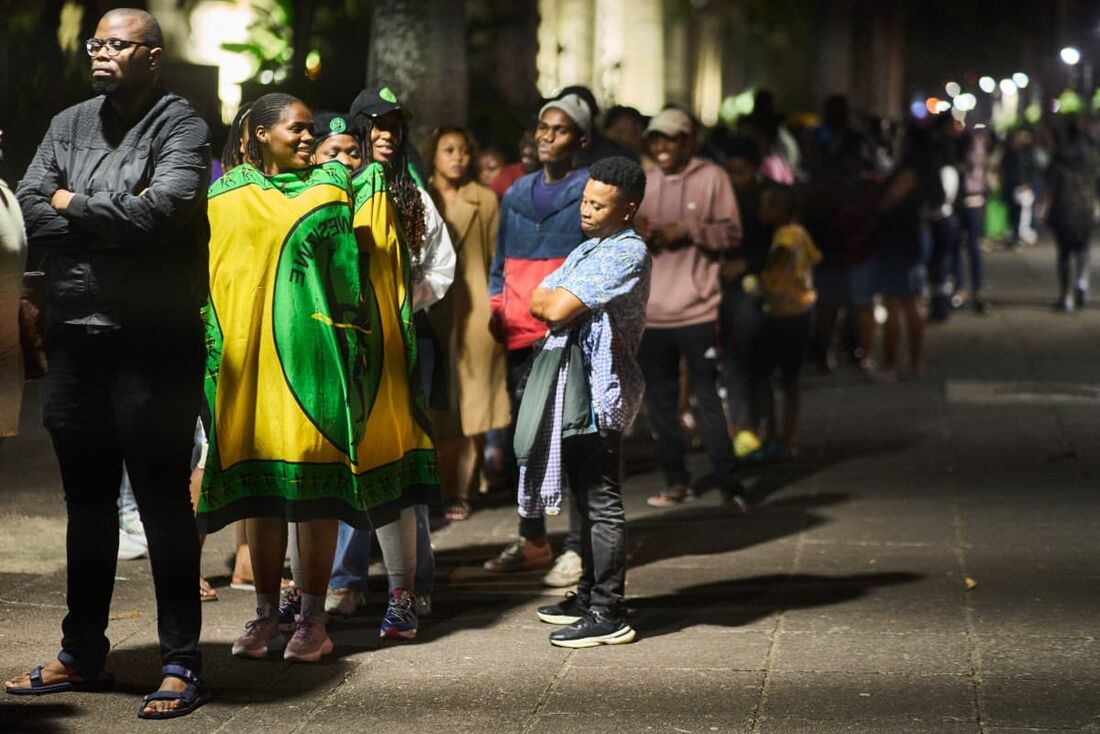 Os eleitores esperam na fila à noite fora do posto de votação da prefeitura em Durban