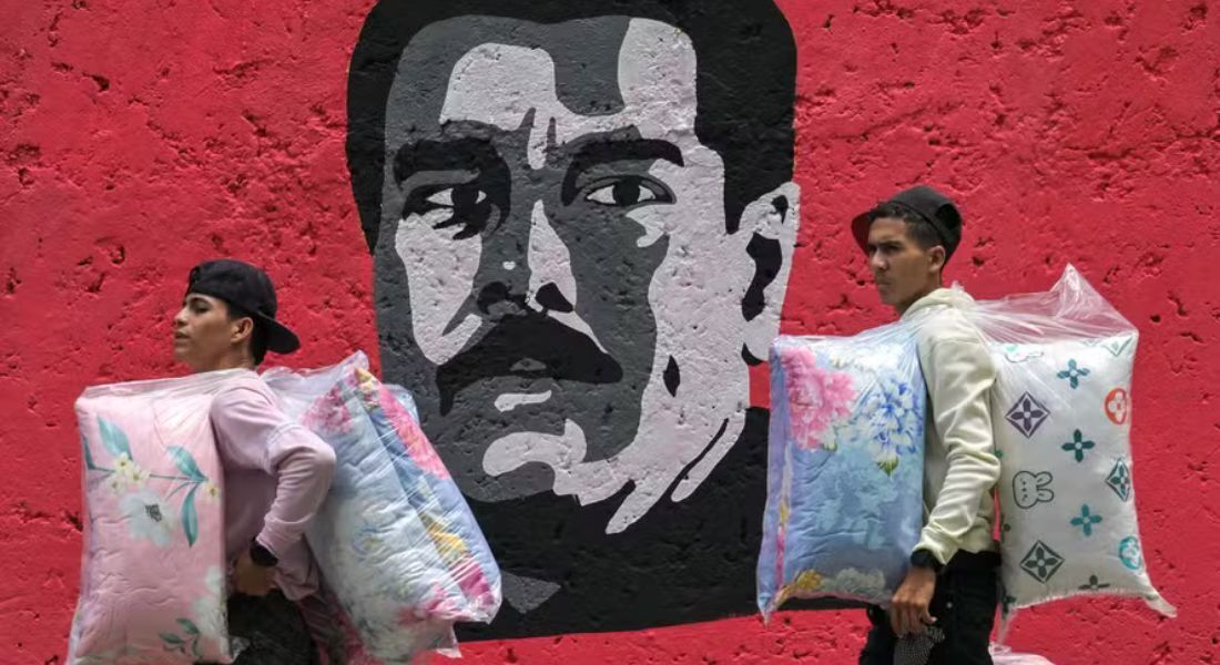 Vendedores passam em frente a grafite do presidente venezuelano, Nicolás Maduro, em Caracas