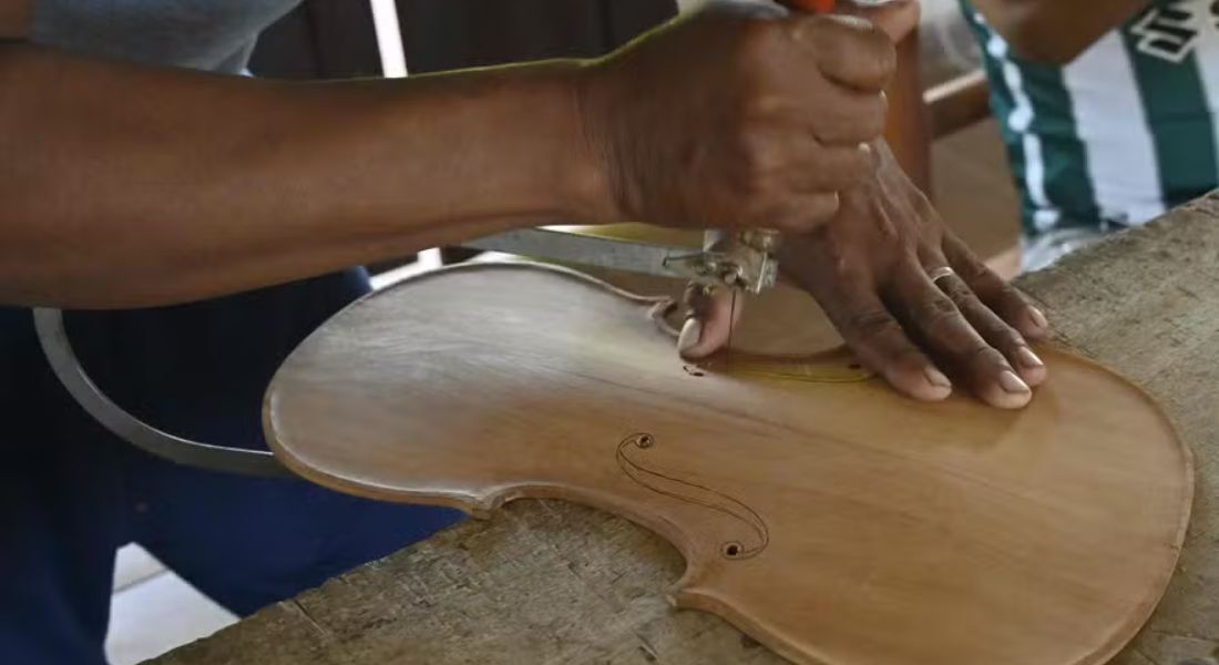 Nelson Orepocanga, aluno da Formacion Artistica Coro y Orquesta Urubicha, esculpe um pedaço de madeira para fazer um violino na cidade de Urubicha