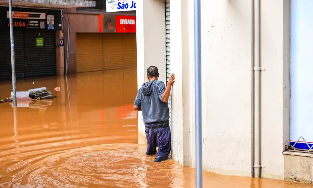 Homem atravessa área alagada em enchente no Rio Grande do Sul