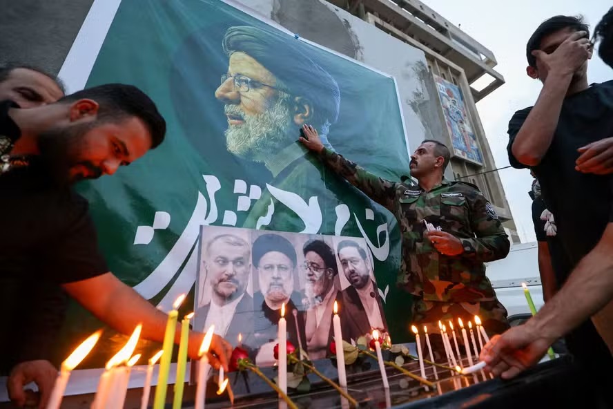 Iraquianos colocam flores e acendem velas para o falecido presidente do Irã, Ebrahim Raisi (foto), do lado de fora da embaixada iraniana em Bagdá 