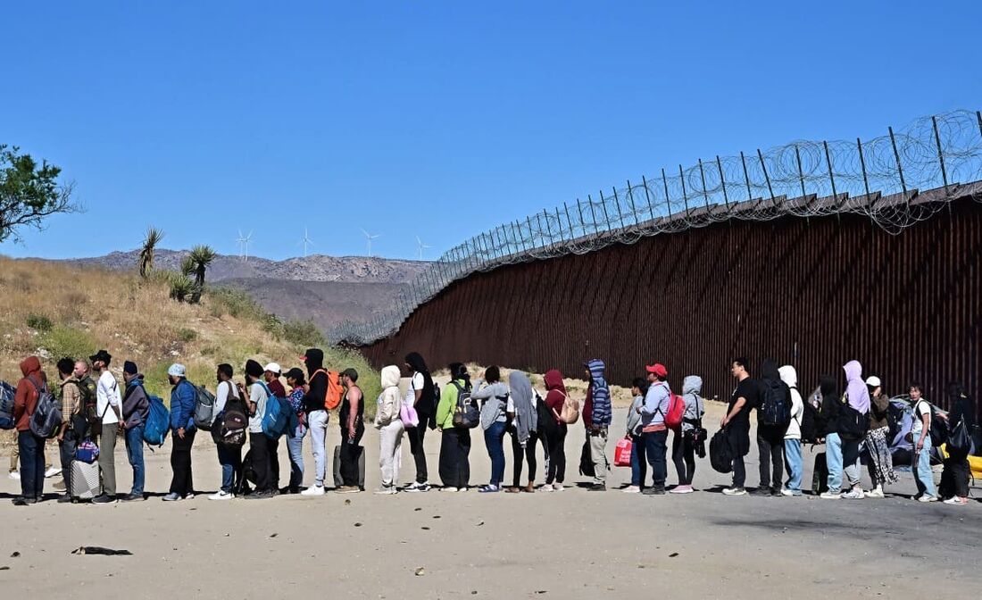 Migrantes esperam na fila pelo processamento dos agentes da Alfândega e da Patrulha de Fronteira depois que grupos chegaram a Jacumba Hot Springs, Califórnia, nos Estados Unidos, após caminharem sob calor intenso do México para os EUA