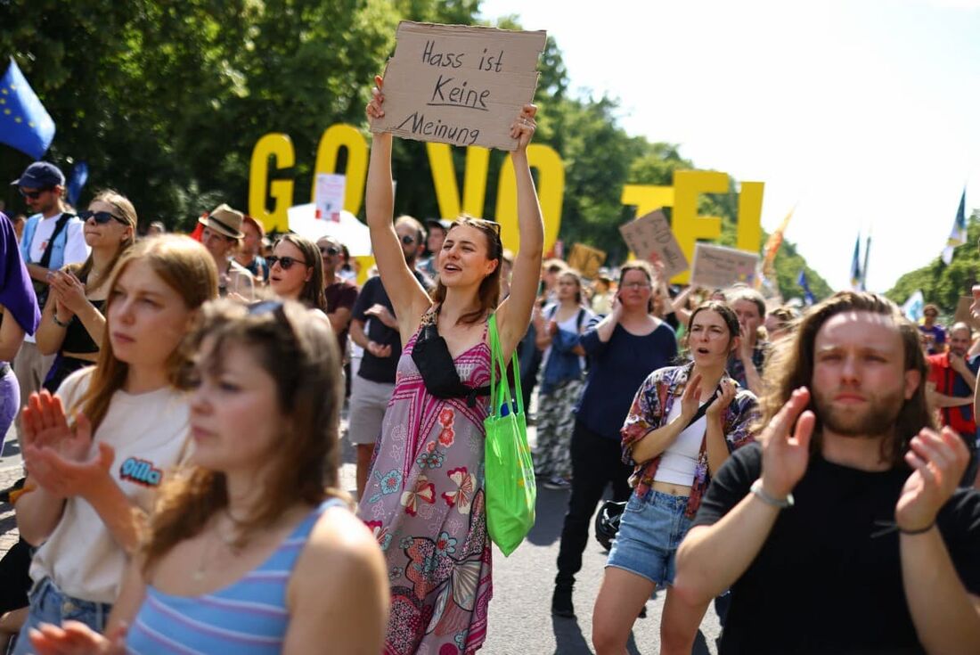 Uma manifestante segura um cartaz onde se lê "O ódio não é uma opinião" enquanto participa numa manifestação para defender a democracia contra a extrema-direita