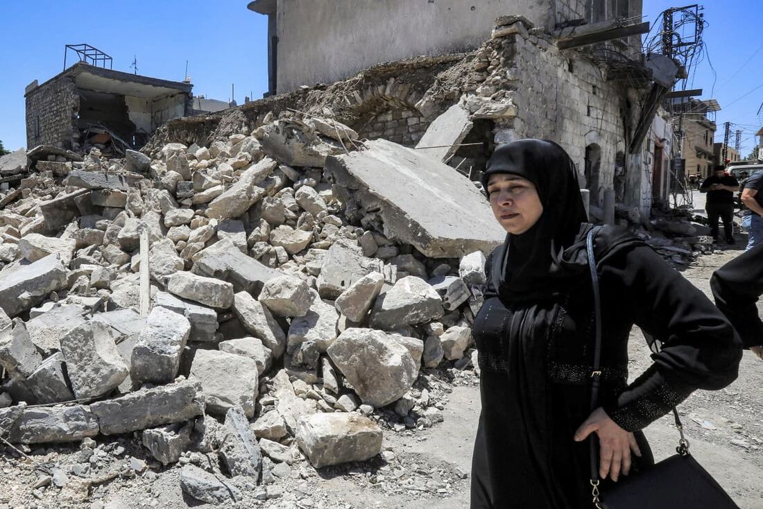 Uma mulher passa pelos escombros de um edifício que foi destruído por bombardeios israelenses anteriores na vila de Yaroun, no sul do Líbano, perto da fronteira com Israel