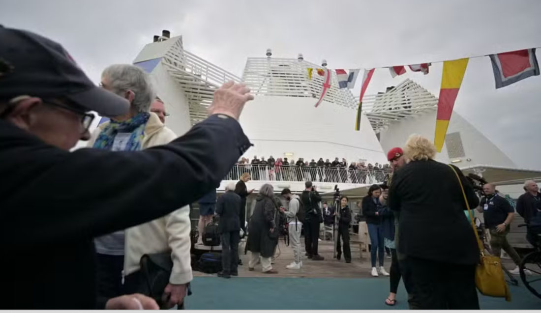 Veteranos do Reino Unido conversam com um oficial militar no convés de uma balsa da Brittany Ferries durante uma viagem à França, perto de Portsmouth, sul da Inglaterra, em 4 de junho de 2024. 