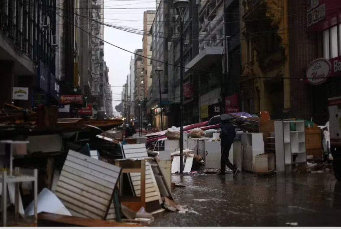 Um homem passa por produtos e estruturas danificadas pelas enchentes descartadas por lojistas em Porto Alegre, Rio Grande do Sul 