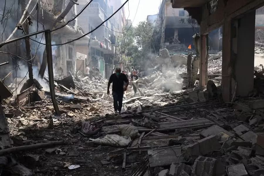 Homem palestino caminha sobre os escombros de edifícios destruídos após uma operação das Forças Especiais Israelenses no campo de Nuseirat, no centro da Faixa de Gaza.