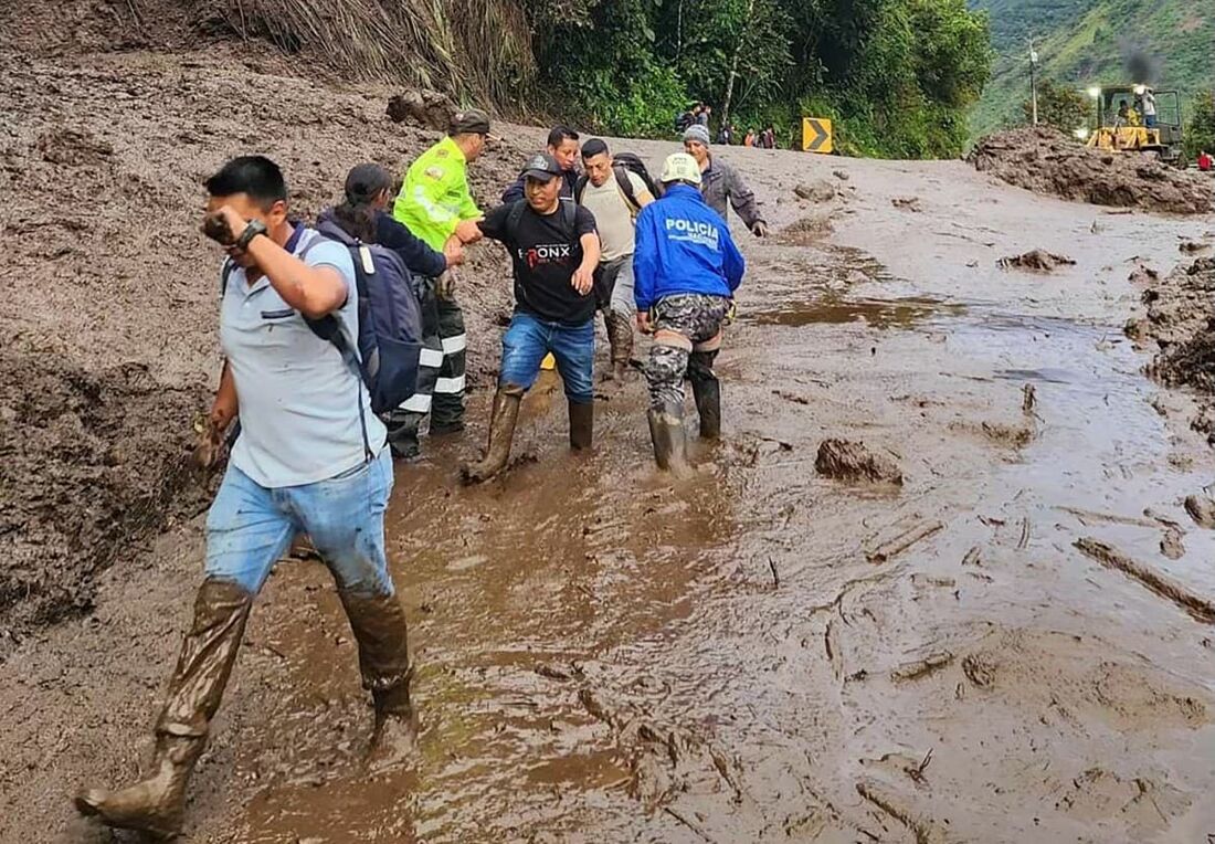 Policiais ajudando civis no local de um deslizamento de terra em Banos, Equador, em 16 de junho 