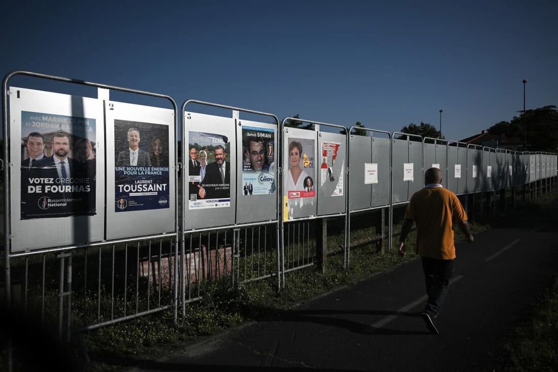 Um homem passa por cartazes eleitorais para as próximas eleições legislativas da França