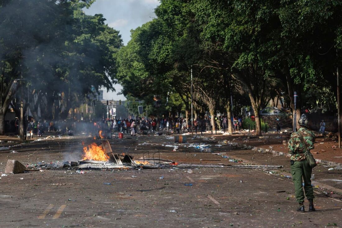 A polícia de choque protege os edifícios do parlamento perto de uma barricada incendiada por manifestantes