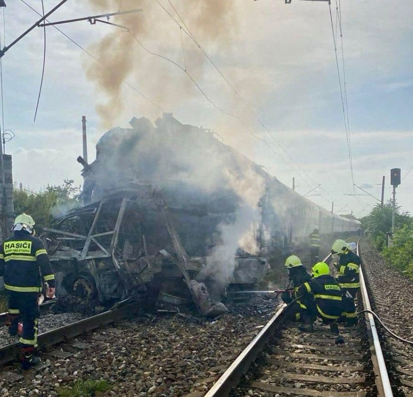 Bombeiros no local do acidente onde um trem de passageiros danificado após colidir com um ônibus