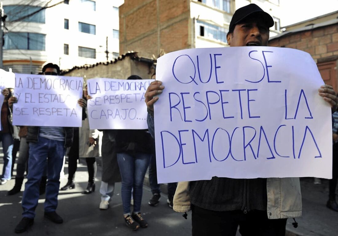 Apoiadores do presidente boliviano Luis Arce seguram cartazes durante uma manifestação em frente à sede da Força Especial de Luta Contra o Crime (FELCC)