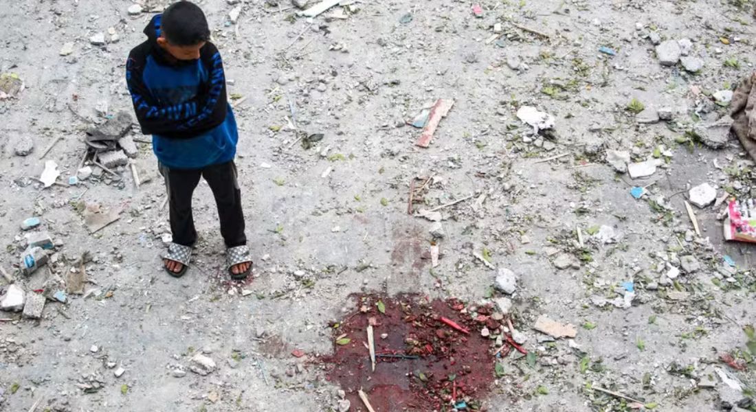 Menino palestino perto de uma mancha de sangue em escola da ONU atingida durante um bombardeio israelense em Nuseirat, na região central da Faixa de Gaza, em 6 de junho de 2024.