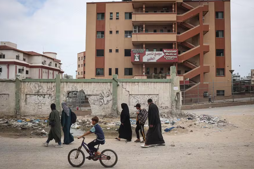 Palestinos passam pelo Hospital Nasser danificado em Khan Yunis, no sul da Faixa de Gaza, em meio ao conflito em curso entre Israel e o grupo militante palestino Hamas