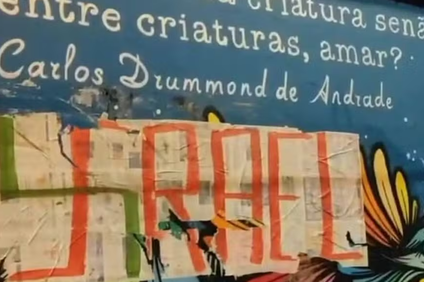 Cartaz com referência a Israel e símbolo nazista colado sobre mural em homenagem a Carlos Drummond de Andrade no Teatro Municipal Sérgio Porto, em janeiro 