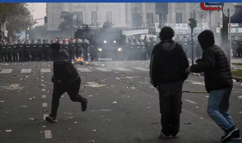 Manifestantes correm durante protesto contra a votação da Lei de Bases no Senado da Argentina