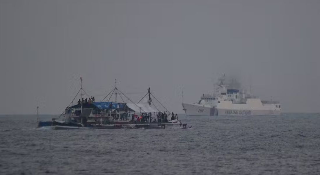 Navio da Guarda Costeira da China (dir.) passa por um barco de pesca filipino no disputado Mar do Sul da China  Foto