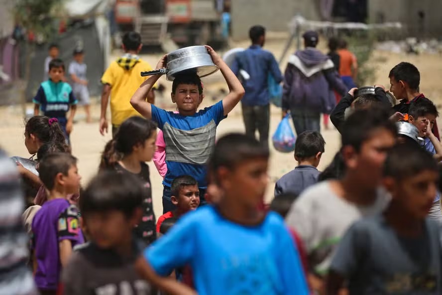 Crianças palestinas deslocadas fazem fila para receber comida em Rafah, no sul da Faixa de Gaza 