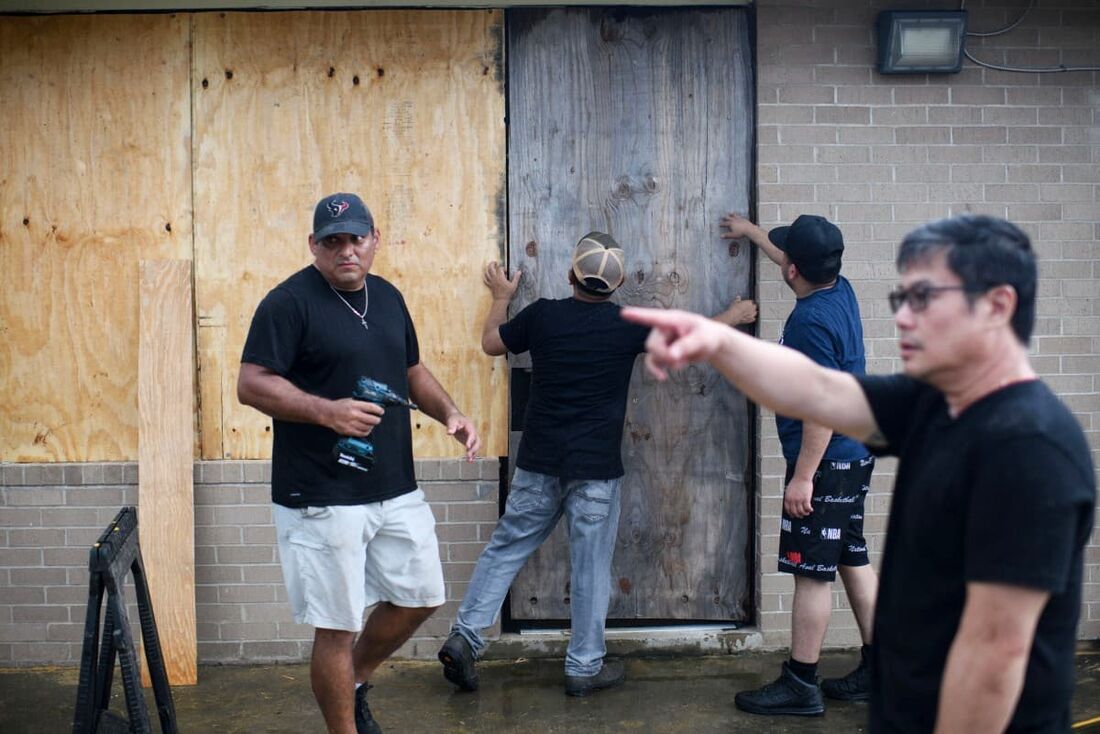 Um grupo de homens fecha um restaurante em Port Lavaca, Texas, enquanto se preparam para a chegada da tempestade tropical Beryl