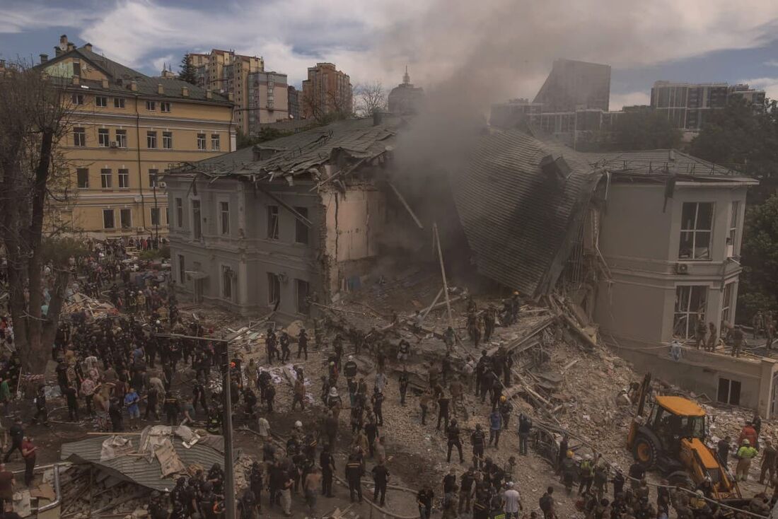 Equipes de emergência e resgate, juntamente com médicos e outros, limpam os escombros do prédio destruído do Hospital Infantil Ohmatdyt após um ataque de mísseis russos na capital ucraniana de Kiev