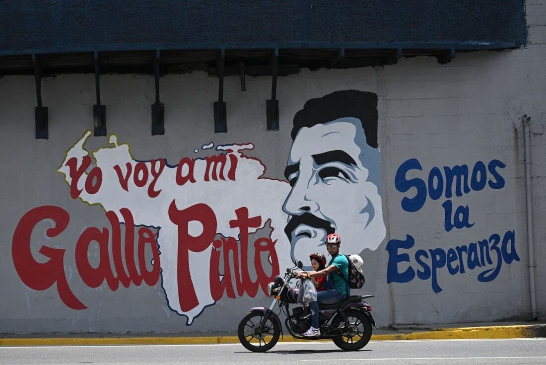  Um motociclista passa por um mural do presidente venezuelano e candidato presidencial Nicolás Maduro 