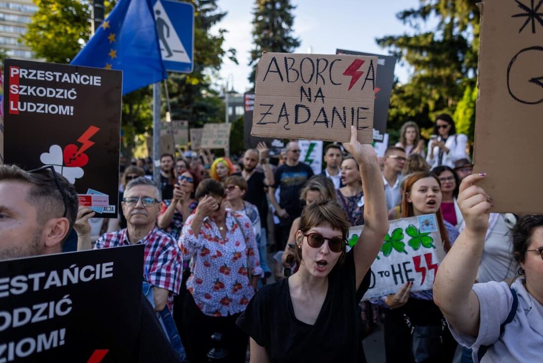 Uma mulher segura um cartaz com os dizeres "Aborto sob demanda" enquanto participa de uma manifestação de mulheres e ativistas pró-escolha