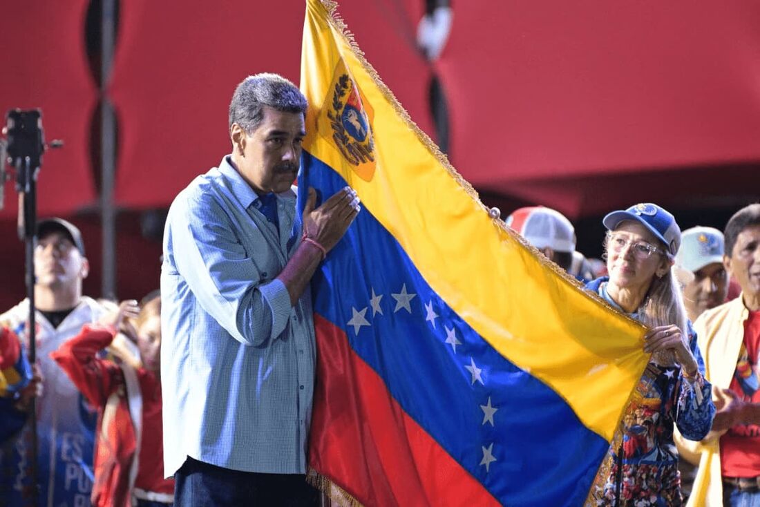 O presidente venezuelano e candidato presidencial Nicolás Maduro (E) segura uma bandeira venezuelana ao lado de sua esposa, Cilia Flores