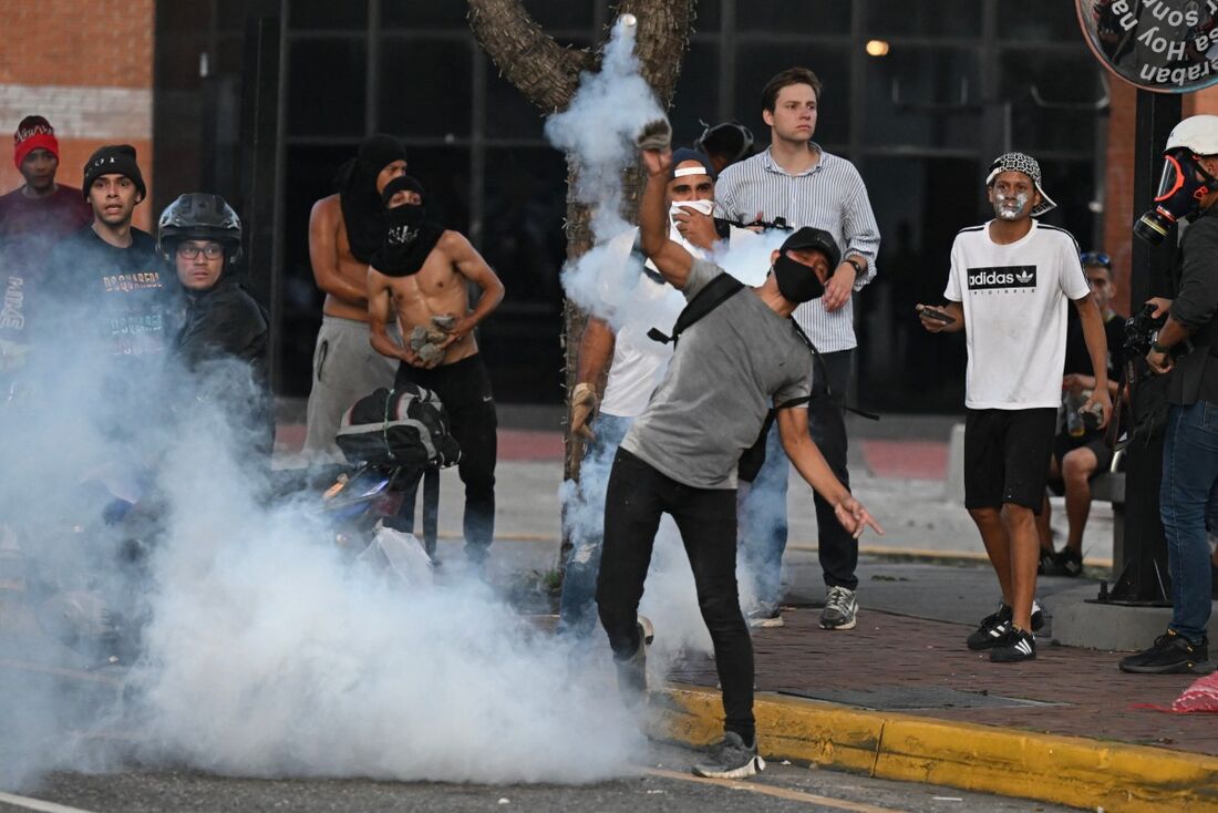 Um manifestante joga de volta para a polícia uma lata de gás lacrimogêneo durante um protesto contra o governo do presidente venezuelano Nicolás Maduro em Caracas 