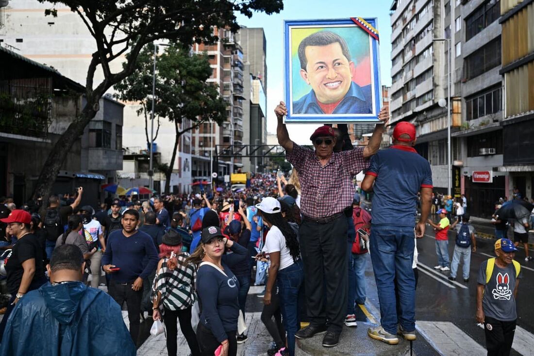 Um apoiador do presidente venezuelano Nicolás Maduro segura uma foto do falecido presidente venezuelano Hugo Chávez durante um comício em direção ao palácio presidencial de Miraflores, em Caracas