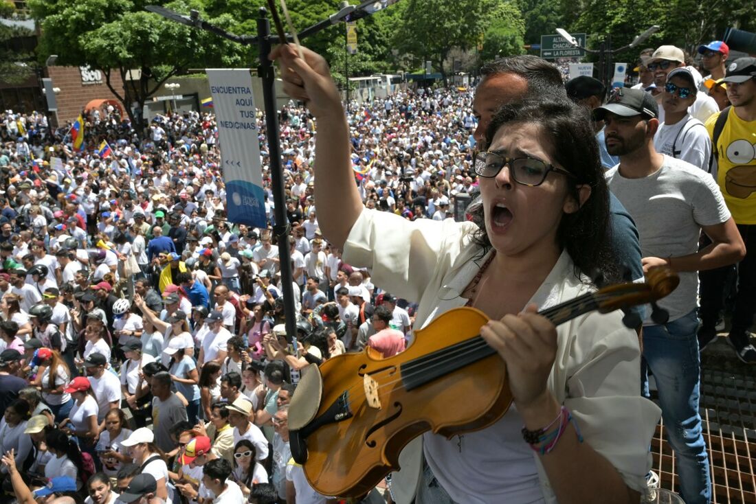 Uma musicista, que se opõe ao presidente venezuelano, Nicolás Maduro, participa de um comício convocado pelo candidato presidencial Edmundo Gonzalez Urrutia e pela líder da oposição Maria Corina Machado, em frente à sede das Nações Unidas em Caracas