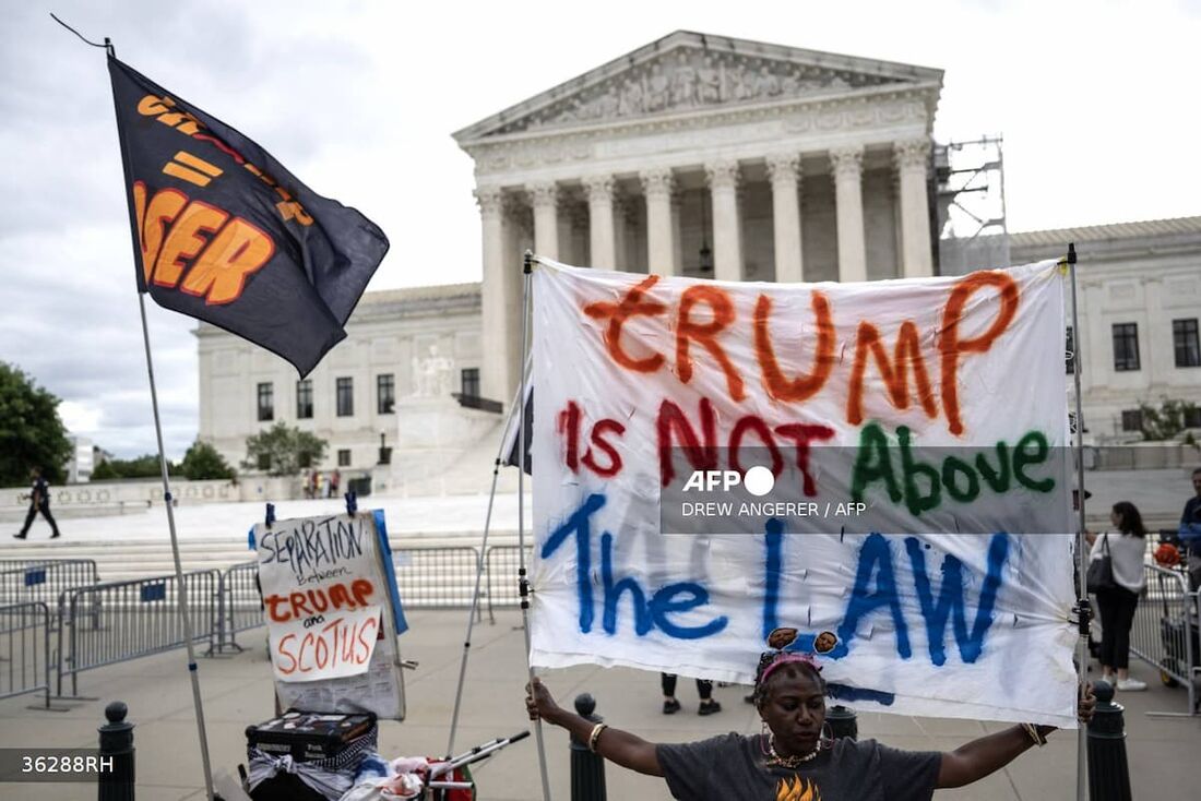 Pessoas seguram cartazes anti-Trump em frente à Suprema Corte dos EUA. O cartaz diz: "Trump não está acima da lei"