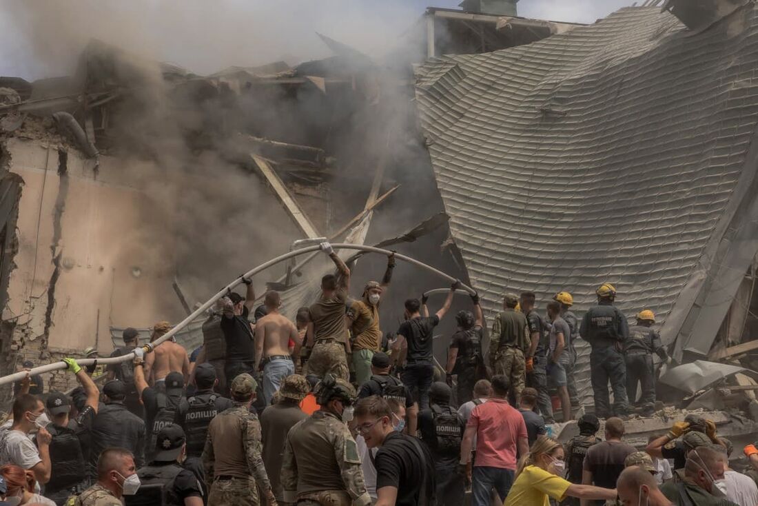 Equipes de emergência e resgate, juntamente com outros, limpam os escombros do prédio destruído do Hospital Infantil Ohmatdyt após um ataque de míssil russo na capital ucraniana de Kiev