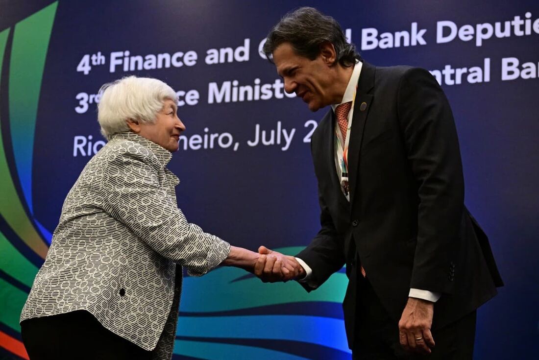 O ministro da Economia do Brasil, Fernando Haddad (D), aperta a mão da secretária do Tesouro dos EUA, Janet Yellen