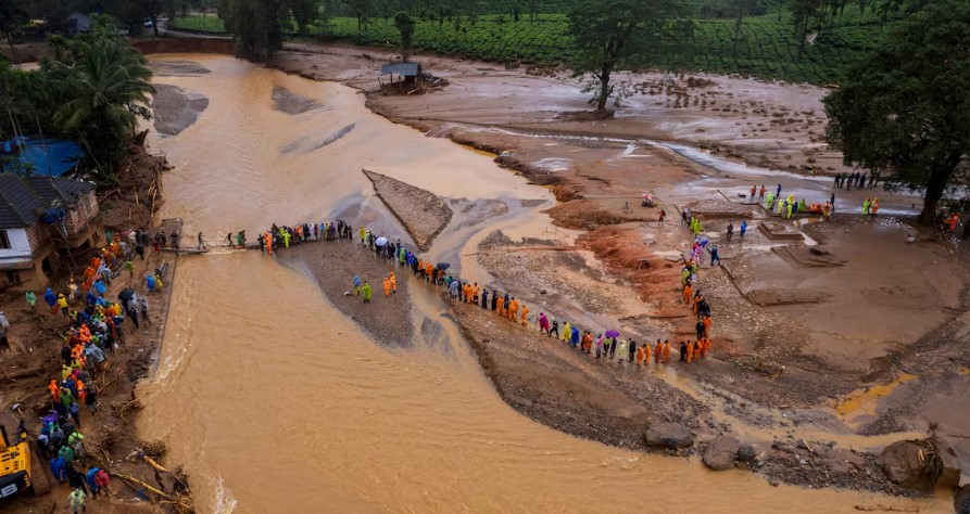 Socorristas atravessam rio por meio de ponte improvisada após deslizamentos de terra na Índia. 