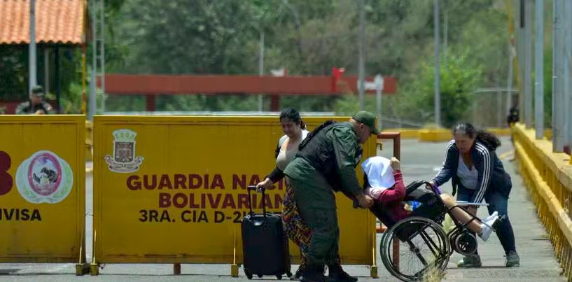 Mulher venezuelana em uma cadeira de rodas é ajudada por um membro da Guarda Nacional Venezuelana na ponte internacional Simon Bolivar após o fechamento da fronteira Colômbia-Venezuela 