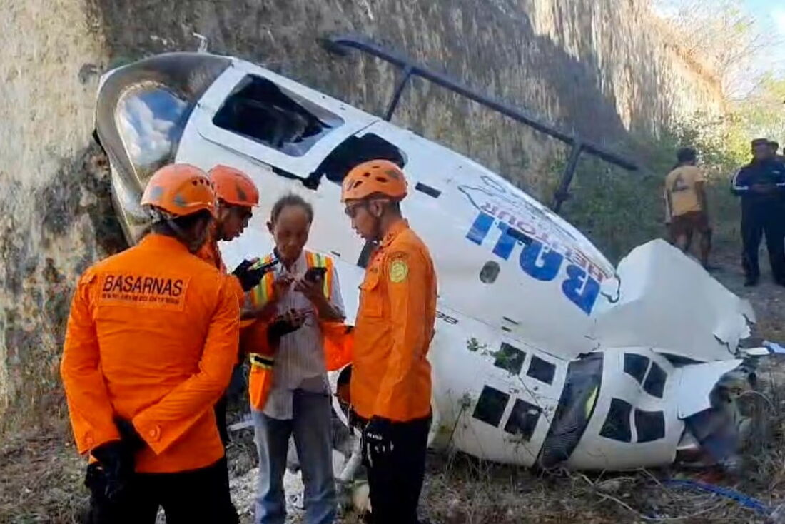 Em imagem divulgada pela Agência de Busca e Resgate da Indonésia (BASARNAS), uma equipe faz inspeção do helicóptero após a queda