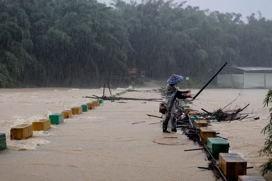 Morador retira galhos de árvores presos na ponte em uma área alagada de Liuzhou, na província de Guangxi 