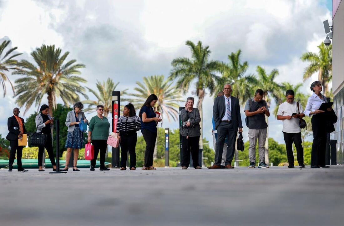 As pessoas fazem fila enquanto esperam a abertura da JobNewsUSA.com South Florida Job Fair na Amerant Bank Arena, em Sunrise, Flórida