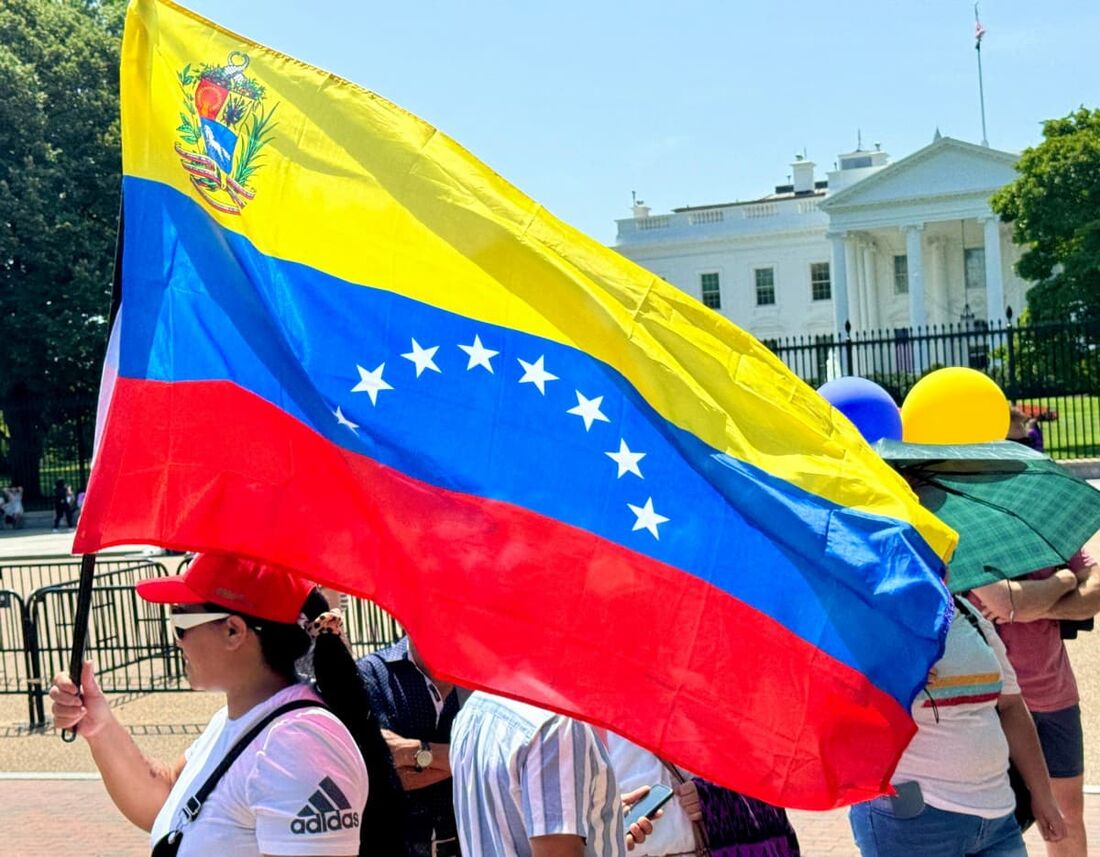 Manifestante segurando bandeira da Venezuela em protesto contra a reeleição o presidente Nicolás Maduro em frente à Casa Branca em Washington, DC