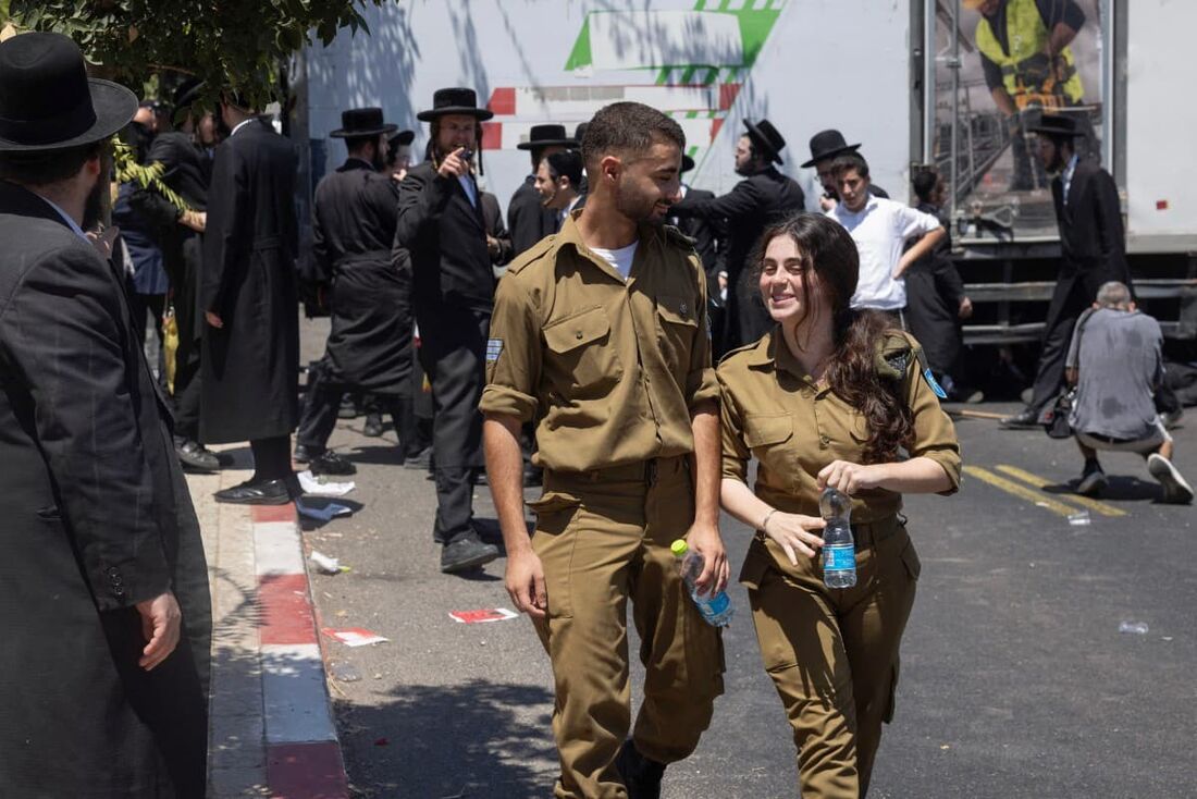 Membros das forças de segurança israelenses passam por manifestantes ultraortodoxos protestando no primeiro dia em que homens judeus religiosos foram solicitados a se alistarem para o serviço militar obrigatório