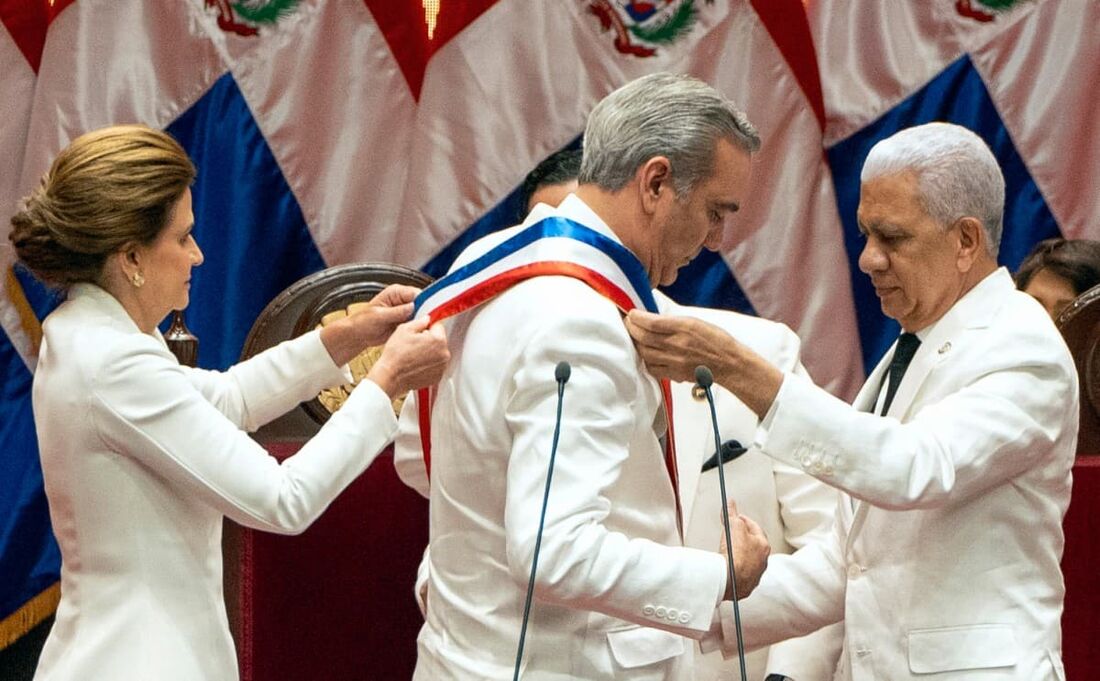 O presidente eleito da República Dominicana, Luis Abinader (C), recebe a faixa presidencial do presidente do Senado, Ricardo de los Santos (D), e da vice-presidente Raquel Pena.