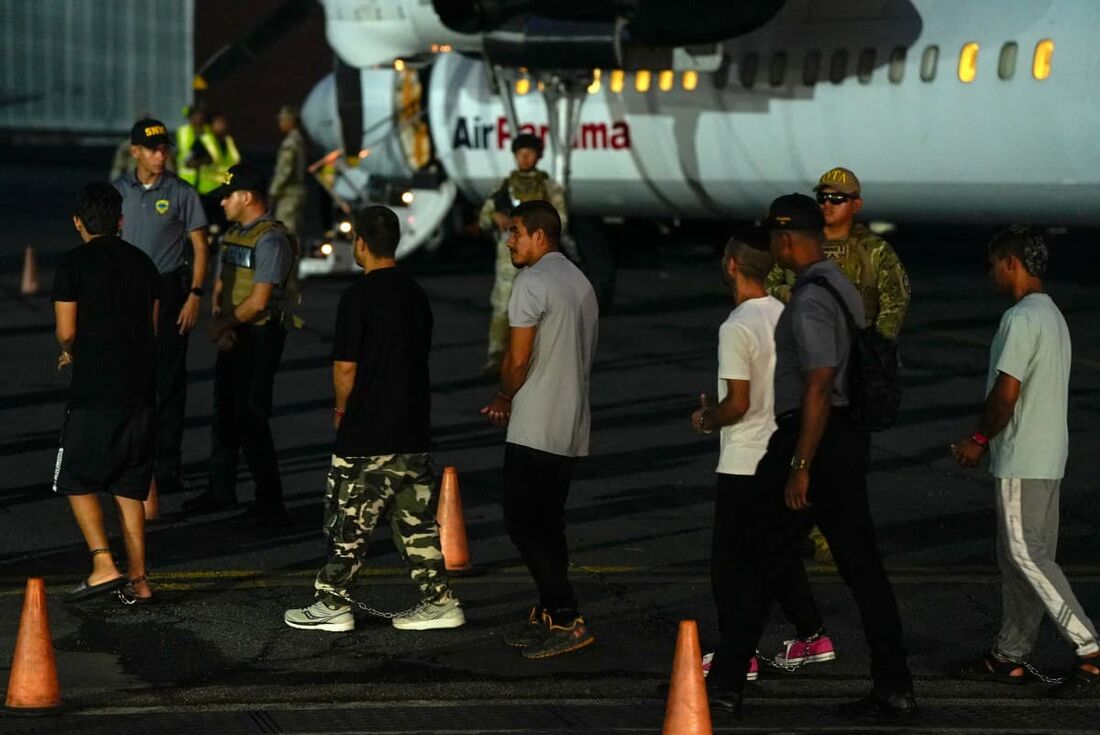 Migrantes colombianos, com as mãos e os pés algemados, fazem fila para embarcar em um avião no aeroporto Albrook Gelabert, na Cidade do Panamá, em 20 de agosto de 2024, durante sua deportação.