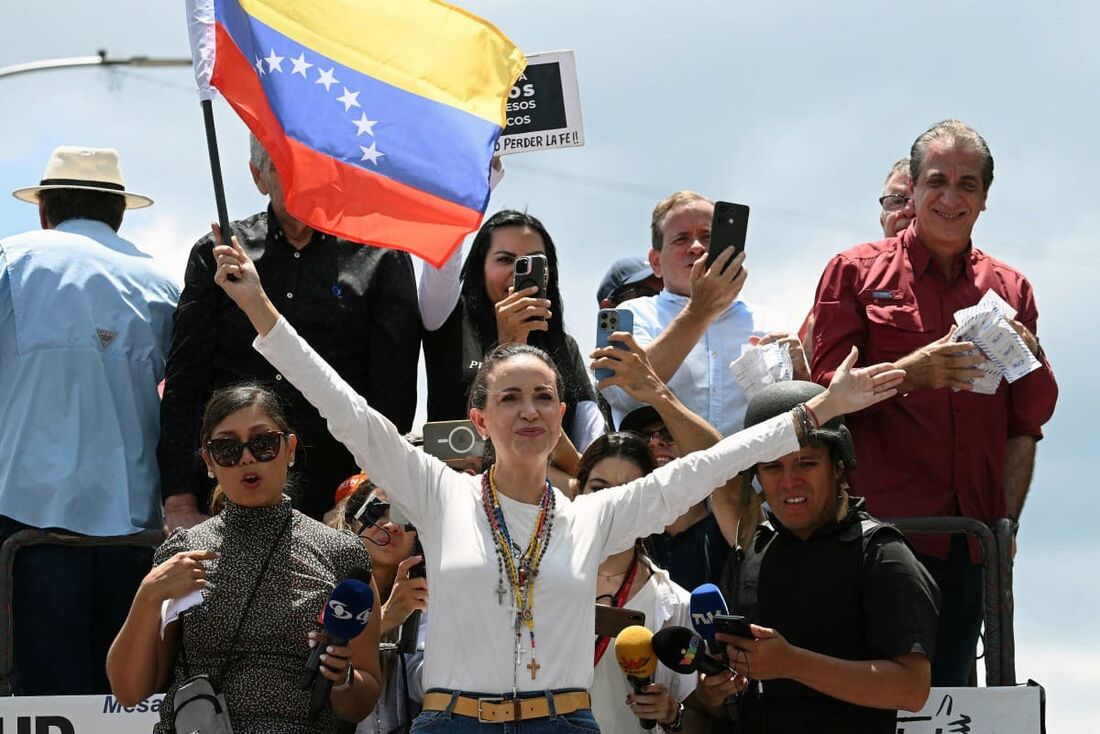 A líder da oposição venezuelana Maria Corina Machado (C) segura uma bandeira nacional no topo de um caminhão durante um protesto convocado pela oposição para que a "vitória" eleitoral seja reconhecida