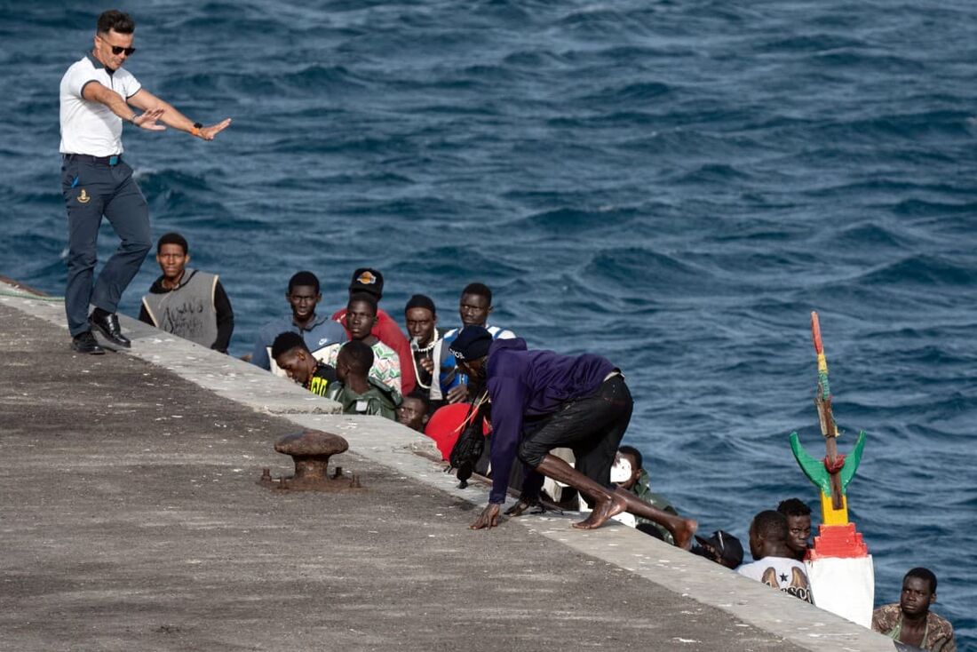 Um capitão do Salvamento Marítimo espanhol (agência de busca e salvamento marítimo) gesticula enquanto uma pessoa desembarca de um barco do Senegal, com 85 migrantes a bordo