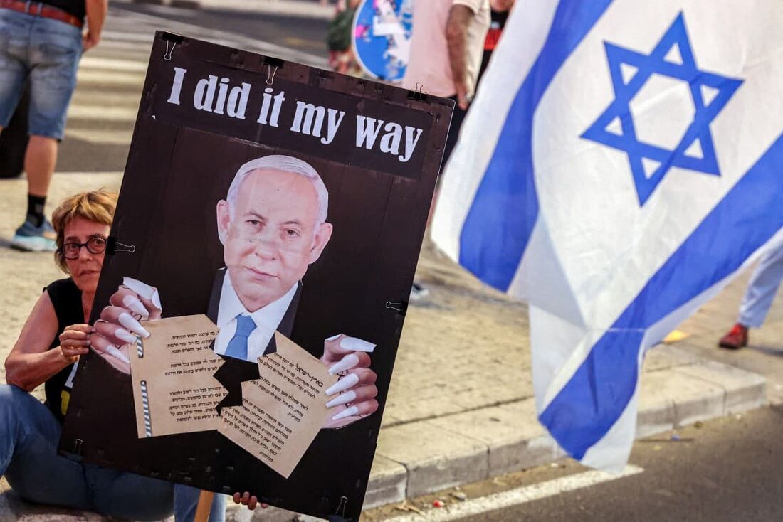 Um manifestante segura uma placa representando o primeiro-ministro israelense Benjamin Netanyahu rasgando a Declaração de Independência de Israel de 1948