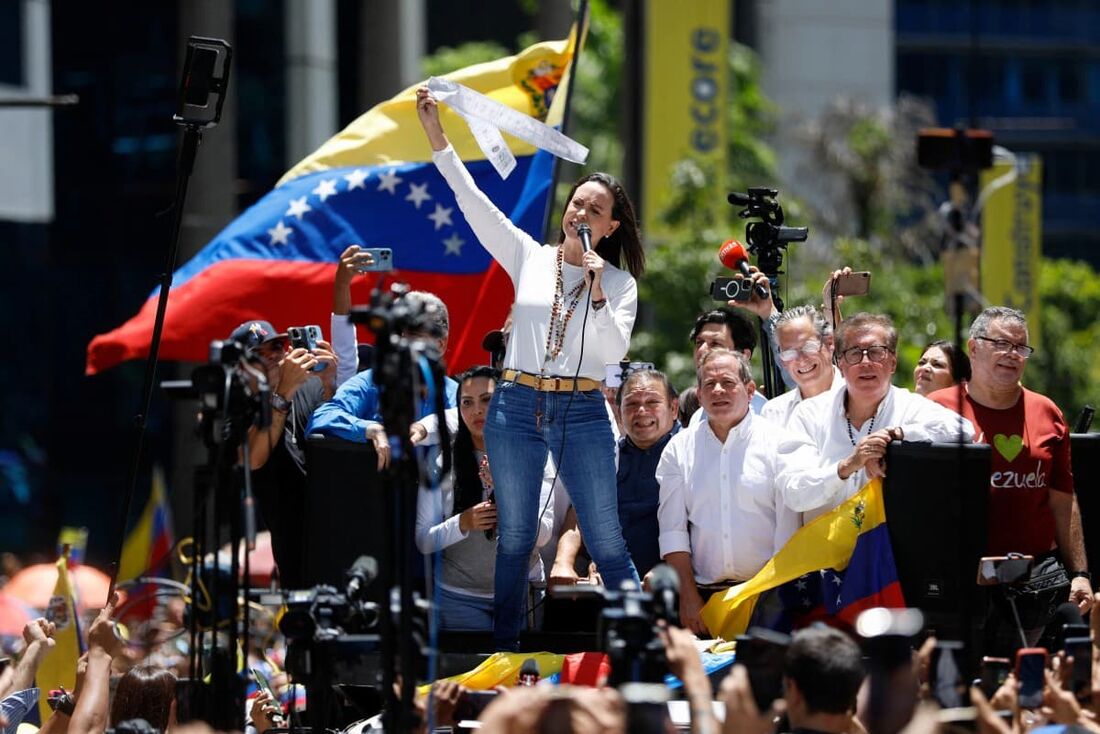 A líder da oposição venezuelana Maria Corina Machado fala com apoiadores enquanto segura registros eleitorais durante um comício em Caracas