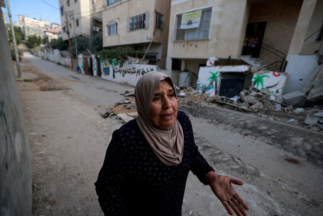 Uma mulher palestina reage enquanto caminha por uma rua danificada durante um ataque do exército israelense no campo de Nur Shams, perto da cidade de Tulkarem, na Cisjordânia ocupada por Israel.